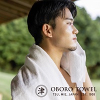 一位男性使用津OBORO毛巾擦拭臉頰，毛巾上印有品牌標誌和地址。