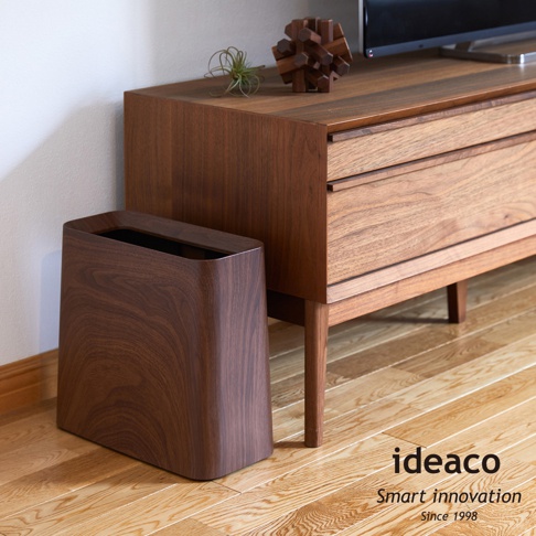 胡桃木紋方形家用垃圾桶，深棕色，具有天然木紋質感，設計簡約，擺放在木製家具旁。