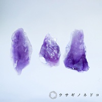 三塊紫水晶原石，呈現不規則的切面與深淺不一的紫色調，部分區域帶有晶體紋理。