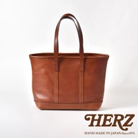 一個棕褐色的皮革托特包，帶有兩個皮革提把，包包正面有縫線裝飾。