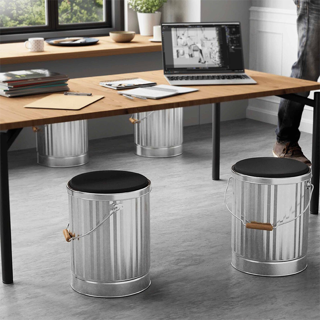 視覺描述模式： 兩個銀色金屬凳子，頂部有黑色坐墊，放在辦公桌下方，桌上有筆記本電腦和文件。