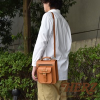 一款棕色皮革製作的兩用單肩包，包身有立體前袋，配有拉鍊和皮帶釦開合，頂部有提把和可拆卸肩帶。