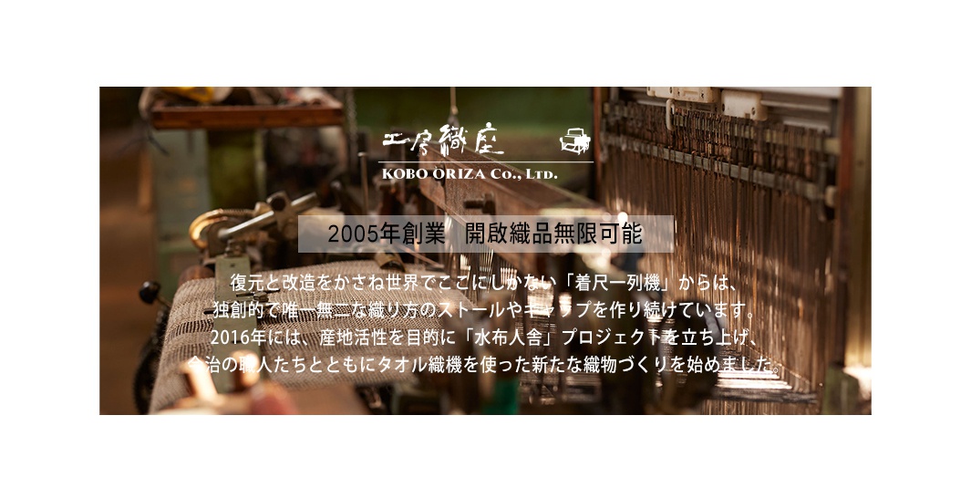 復古織機特寫，展示木製結構與金屬零件，背景為織布。上方有日文與英文公司名稱 KOBO ORIZA Co., Ltd.，下方有日文文字說明。