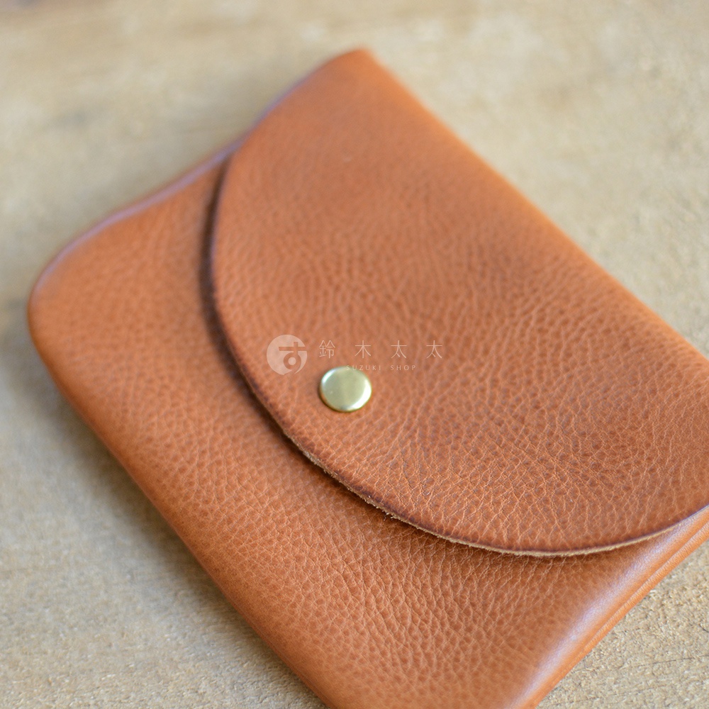 職人手作皮革小物收納袋，採用棕褐色柔軟皮革製成，設有鈕扣式翻蓋，材質呈現細緻紋理，適合收納各式小物。