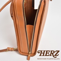 棕色皮革商務電腦後背包，拉鍊部分特寫，展示精緻縫線與黃銅色拉鍊頭，皮革材質顯現自然紋理。