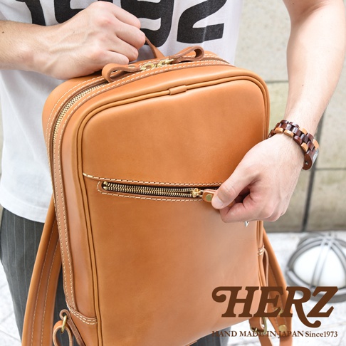 職人手作皮革長方型後背包，溫潤的棕褐色皮革，搭配黃銅色拉鍊與縫線，設計簡約，前方有拉鍊暗袋，適合日常攜帶。