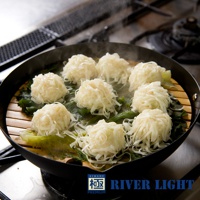 黑色的 30 公分炒鍋內，擺放著竹蒸籠，蒸籠上層層疊疊著數個白色、外觀類似燒賣的食物，食物表面覆蓋著細絲狀的配料，下方襯著綠葉菜，鍋中冒著蒸氣。