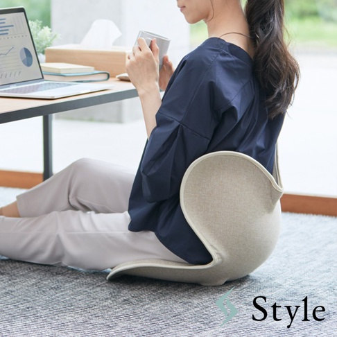 Style Standard II 美姿調整椅 II，一名女性坐在地毯上，使用電腦並手持杯子，椅子的布料是米色。