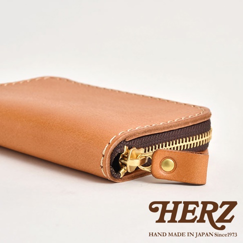 職人手作皮革多用途收納鑰匙包，採用淺棕色皮革，搭配金屬拉鍊與皮革拉帶，縫線清晰，展現簡約質感。