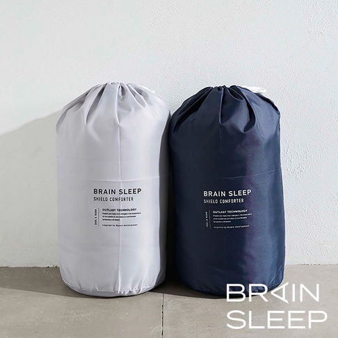 太空科技調溫被-雙人被，左為淺灰色，右為深藍色，兩款皆為抽繩束口收納袋裝，印有「BRAIN SLEEP SHIELD COMFORTER」字樣及相關技術說明。