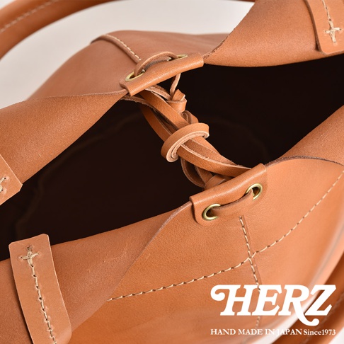 棕色皮革球形肩掛托特包，展示皮革編織細節、金屬孔眼和手工縫線。