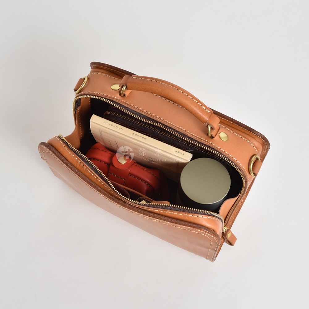 職人手作皮革兩用方形單肩包 CW-9，淺棕色，展示包內有書籍、紅色小物和圓形容器。