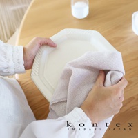 MOKU Organic 有機棉長毛巾，淺米色，織有細緻紋理，用於擦拭白色盤子。