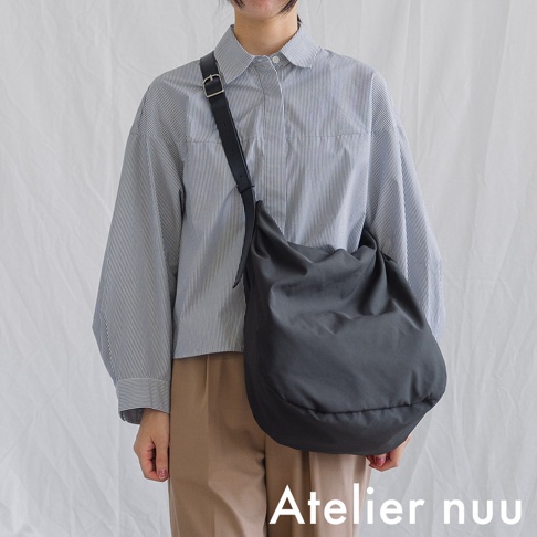 Atelier nuu ssent 肩背包，由身穿條紋襯衫和卡其色褲子的模特兒展示