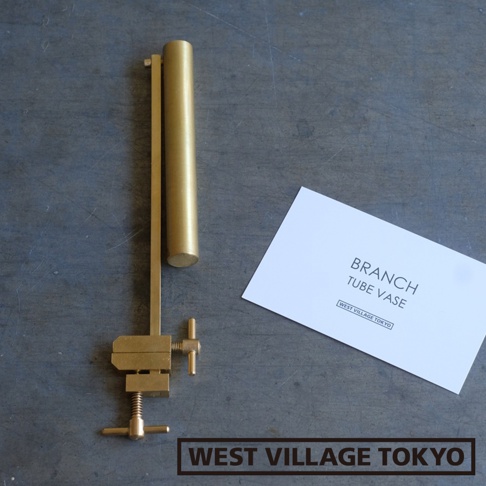黃銅可夾式金屬花器，由黃銅製成，呈圓柱形，帶有可調節的夾具和手柄，旁邊放著印有「BRANCH TUBE VASE」字樣的白色卡片。