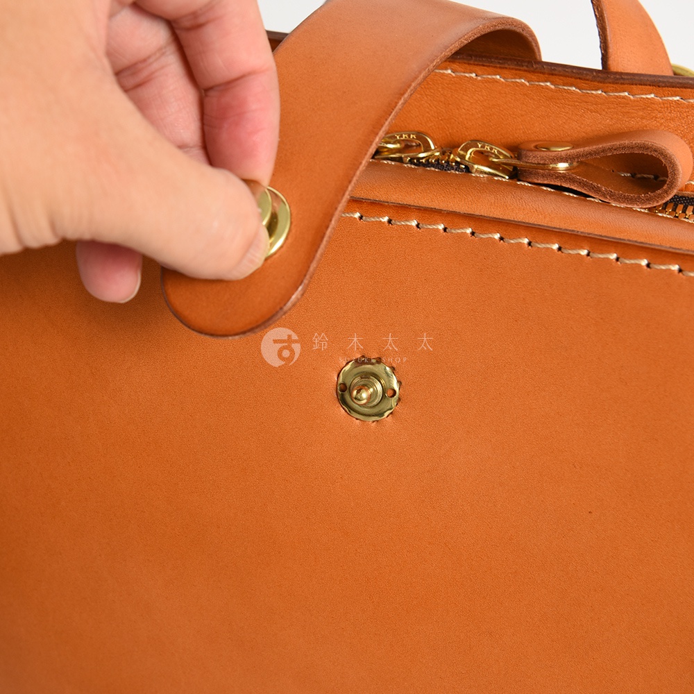 職人手作皮革商務休閒兩用後背包 R-36，特寫展示棕色皮革材質、金色金屬壓扣及 YKK 拉鍊細節，皮革表面呈現自然紋理。