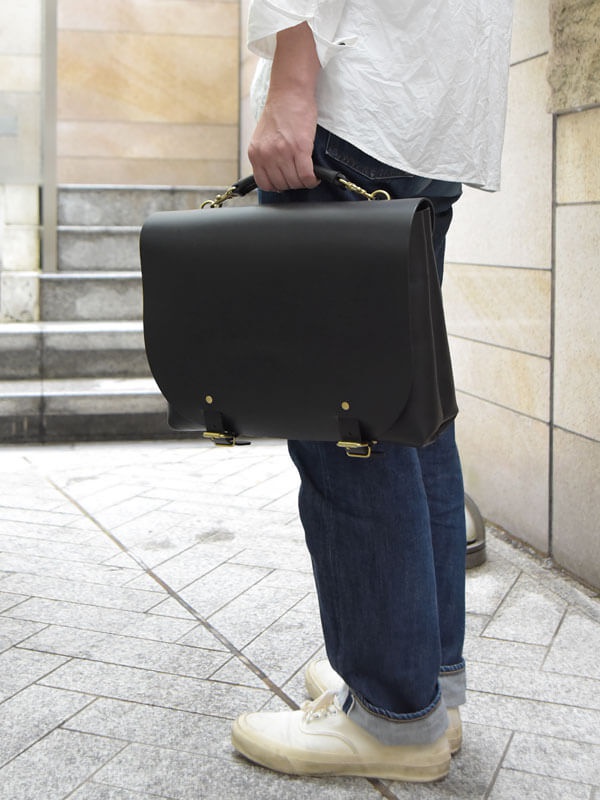 職人手作皮革雙扣兩用側背包 (CW-137) M，黑色皮革，配有金色搭扣和提把，可手提或肩背。