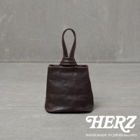 職人手作皮革Organ單柄手提包，深棕色，採用柔軟皮革製作，包身方形，頂部有單個提把，提把處以皮革繩結設計，包身縫線明顯，整體風格簡約。