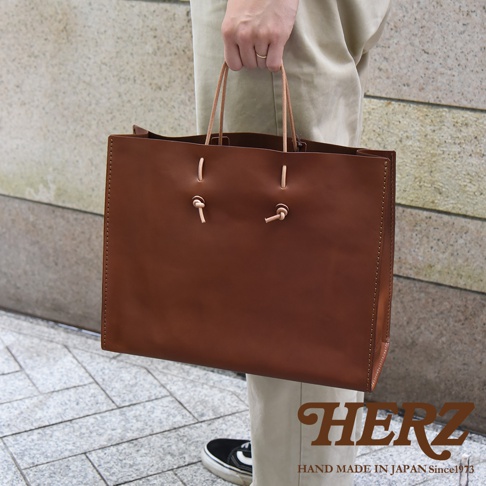 職人手作皮革提袋 T-5，棕色，由光滑皮革製成，配有圓形皮革提把，透過皮革繩結固定，簡潔大方的設計，適合日常攜帶。