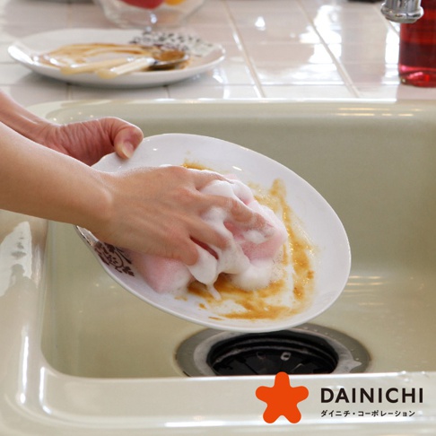 粉紅色海綿正在清洗帶有污垢的白色盤子，盤子上有泡沫。