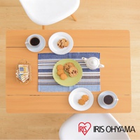 木質桌面上擺放著咖啡杯、餅乾、茶壺和編織籃，桌上有兩個白色圓盤，其中一個裝有餅乾，另一個裝有兩塊花形餅乾。