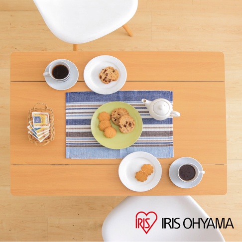 木質桌面上擺放著咖啡杯、餅乾、茶壺和編織籃，桌上有兩個白色圓盤，其中一個裝有餅乾，另一個裝有兩塊花形餅乾。