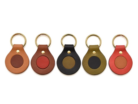 五個職人手作皮革圓形鑰匙圈，分別為棕色、紅色、黑色、軍綠色和紅褐色，均配有黃銅色鑰匙圈，整體呈水滴狀，中間鑲嵌同色系或對比色圓形皮革。