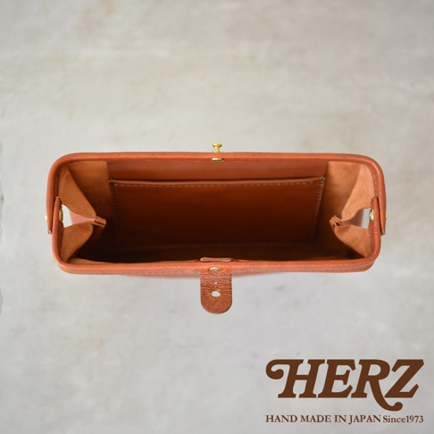 棕色皮革手拿包，頂部視角，展示內部隔層與金色金屬釦。