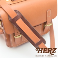 職人手作皮革肩墊，採用咖啡色與橘棕色皮革拼接，搭配金屬釦環，展現細膩車縫工藝。