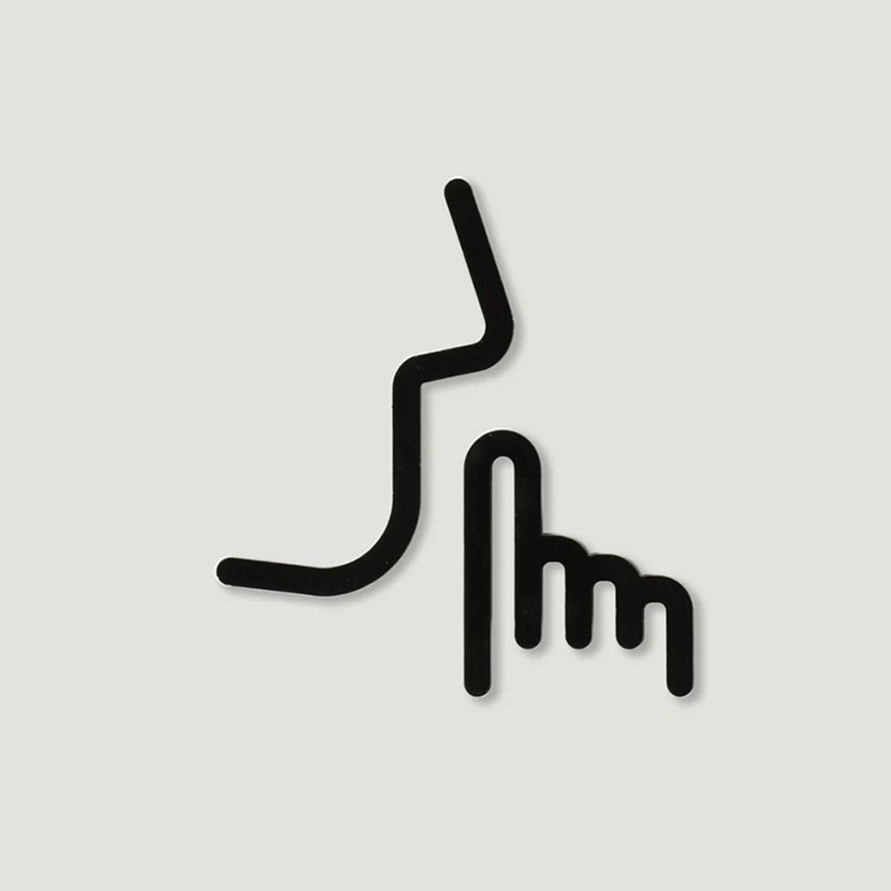 黑色線條勾勒出的「請安靜」圖示，包含一張側臉輪廓和食指豎起放在嘴唇前的動作，材質為金屬。