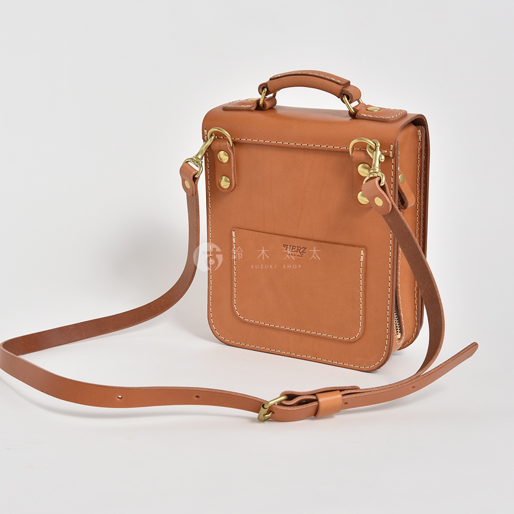 職人手作的棕色皮革立體口袋兩用單肩包，採用堅固的車縫線和金屬扣環，可肩背或手提。