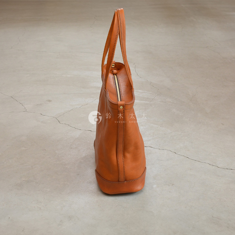 職人手作皮革Organ肩背拉鍊托特包，採用溫暖的棕褐色皮革製成，包身線條簡潔，配有拉鍊封口和寬版手提帶，展現簡約實用的風格。