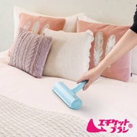 淺藍色免耗材抗菌棉被除塵刷，置於床鋪上，旁邊有粉色、紫色和白色靠墊，其中粉色靠墊印有白色羽毛圖案，白色靠墊為蕾絲編織。