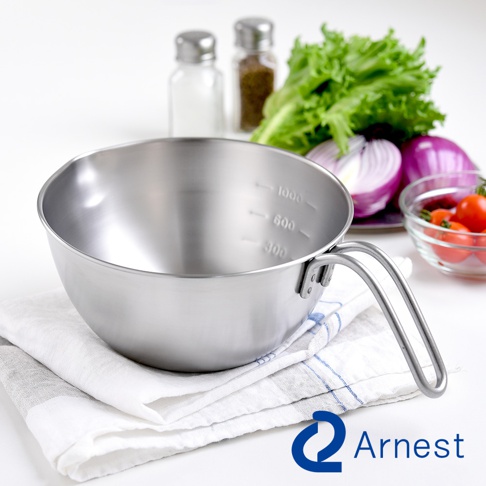 Arnest 不鏽鋼多用途單柄調理碗，附有 300ml、600ml、1000ml 的刻度，旁邊擺放著鮮綠的生菜、紅色洋蔥和幾顆小番茄。