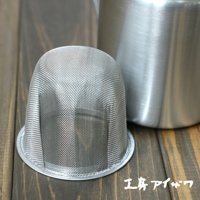 一個不鏽鋼霧面直筒茶壺，配有一個銀色網狀茶濾，放在木質桌面上。