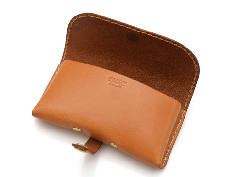 棕褐色皮革製成的眼鏡收納盒，翻蓋設計，帶有金屬扣帶。內裡為深棕色皮革，表面壓印有品牌標誌。