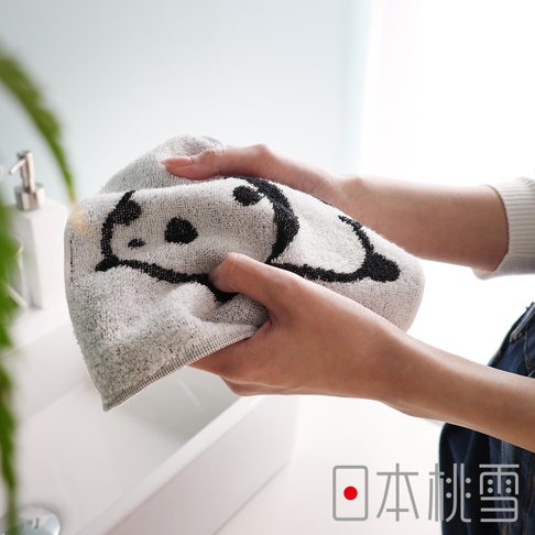 日本桃雪的可愛熊貓圖案純棉手帕，由雙手握住，展示在洗手台上方。