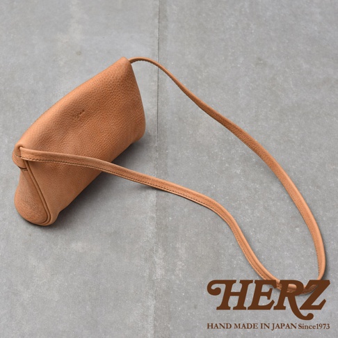 M-8 尺寸的職人手作皮革貼身斜背包，呈現自然的淺棕色皮革紋理，搭配細長的同色系斜背帶。