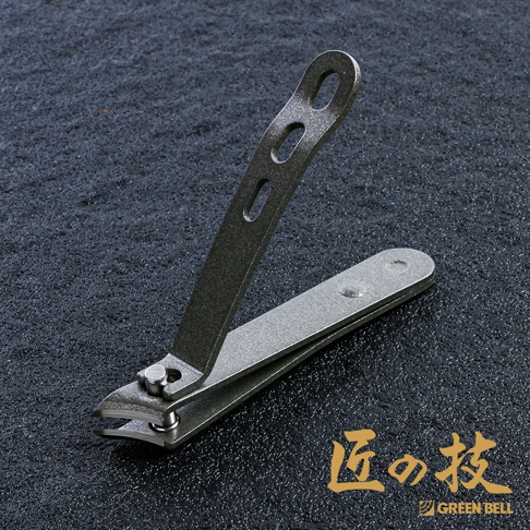一體成型金屬足甲剪，表面呈現細緻的磨砂質感，顏色為深灰色。其上部握柄為長條形，帶有三個不同大小的橢圓形孔洞，方便使用者抓握。整體結構堅固，設計簡約。