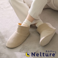 一雙米白色格紋布料的包覆式腳踝室內拖鞋，內裡為絨毛材質，由穿著白色長褲與條紋襪子的人穿著，置於灰色地毯上。