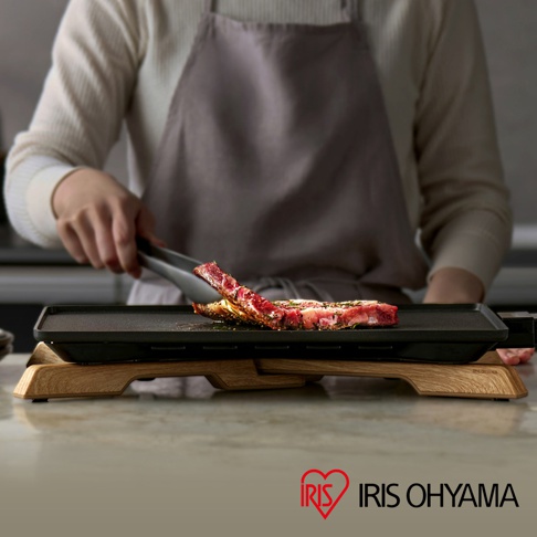 伊瑪 IHU-A10-B 輕薄電烤盤，黑色烤盤搭配木質支架，正在烹調一塊帶骨牛排。
