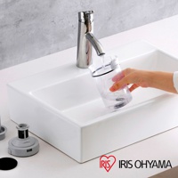 一個透明集塵杯正在被沖水，旁邊是一個白色水槽，水槽旁有吸塵器的灰色配件。