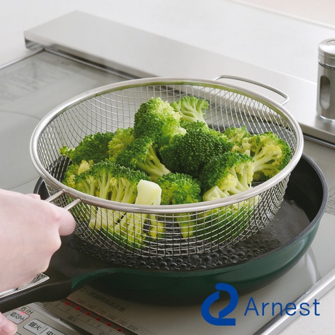 逸品物創不鏽鋼手持料理濾網，裝滿綠色花椰菜，正在滾水中瀝水。濾網為圓形金屬網狀，附有兩個手柄，置於綠色深鍋上方。