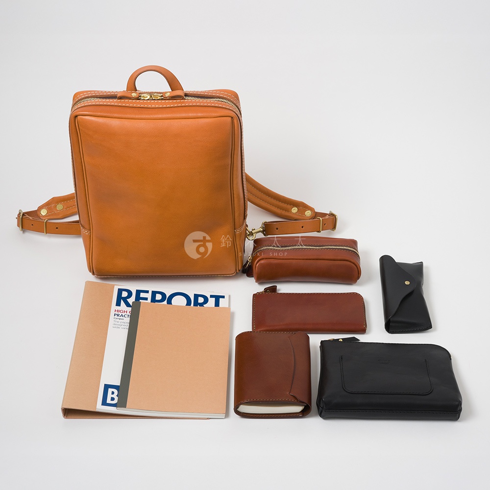 質感棕色皮革後背包，搭配同色系化妝包、長夾、短夾、筆記本及黑色皮夾，呈現豐富的皮革配件組合。