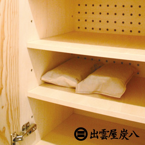 木質櫃內，淺褐色布料包裝的兩件調濕木炭，一左一右置於木製層架上。櫃門鉸鏈為銀色金屬。