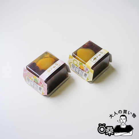 兩個方形的小型日式和菓子放在白色背景上，每個包裝頂部均可見完整的蜜漬栗子與紅豆顆粒，外層包裝紙帶有精緻的淡粉色與黃色花紋，印有日文花利休字樣，呈現出優雅的禮盒甜點風格。