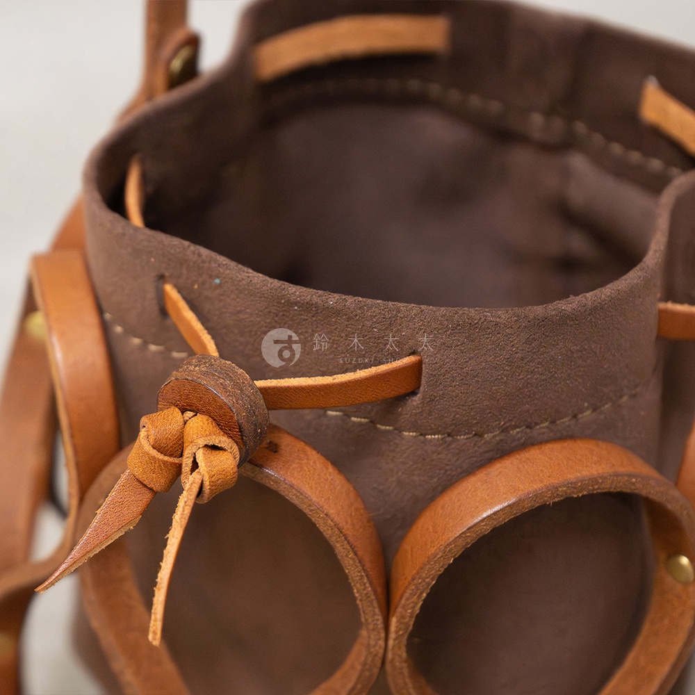 日本HERZ職人手作皮革Organ編織水桶包 G-98 棕色，展示包包細節，包含皮革編織、抽繩設計及品牌標誌。