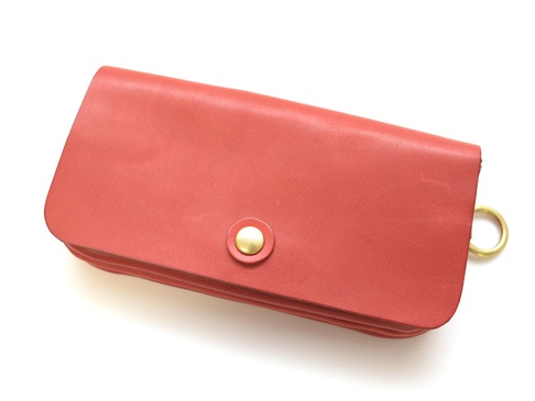 桃紅色皮革長夾，設有金色金屬按扣和側邊金色圓環，展現多層次結構。