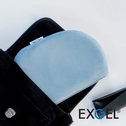 THE OWL 進階款隨身坐墊，淺藍色，柔軟織物表面，呈現半圓弧形，置於黑色包袋中，旁邊為黑色皮質小物。