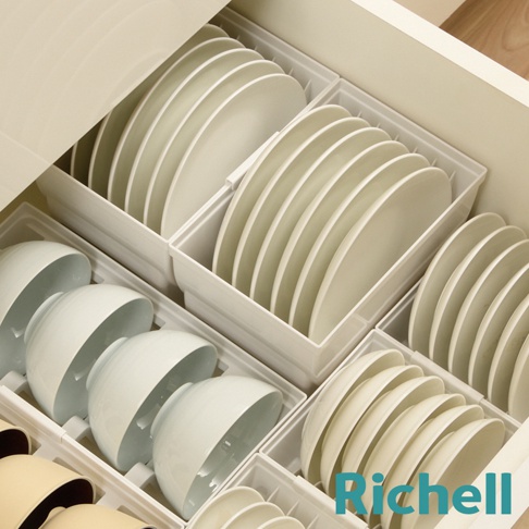 抽屜式餐盤收納架內整齊擺放著多個白色碗盤，碗盤被白色隔板分隔開，下方還有部分淺黃色杯子。